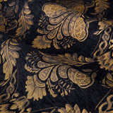 Close-up of Shiraz Jacquard Chenille Pencil Pleat Curtains in black, showing a woven gold floral damask pattern with scalloped and scroll motifs on draped fabric.