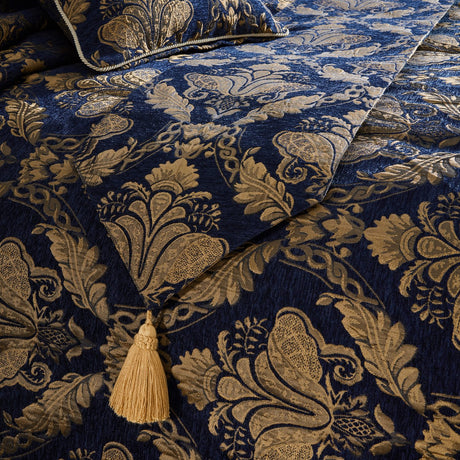 Shiraz Jacquard Chenille bed runner in navy with a gold damask floral pattern, woven texture, and a large gold tassel detail, styled across a bed.