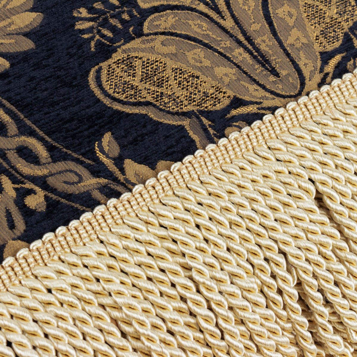 Close-up of the Shiraz Jacquard Chenille Throw in black, showing gold floral damask weave alongside a knotted cream fringe trim.