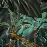 Siona Cotton Jungle Duvet Cover Set in Multi, close-up of a peacock among dense green tropical foliage on a dark ground with a matching pillowcase.