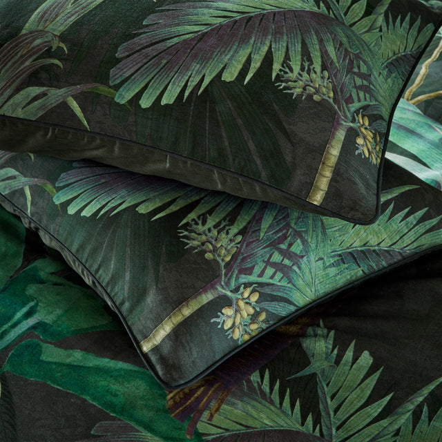 Siona Jungle Cotton Pillowcase Pair in Multi, shown stacked with a dense tropical palm print in green tones and amber-gold fruit clusters on a near-black ground, finished with a plain trim edge.