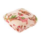 Folded polyester fleece throw in cream with a printed reindeer and Christmas tree design in pink, red, green and brown, shown on a white background.