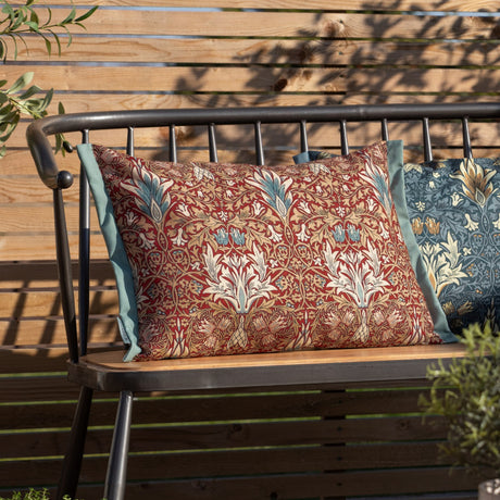 Rectangular Snakeshead Floral polyester cushion in berry red with tan, cream and teal floral pattern and sage-green Oxford trim, shown on an outdoor bench.