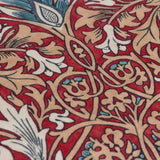 Close-up of the Snakeshead Floral polyester cushion in Berry, showing William Morris style scrolling foliage and stylised flowers in tan, cream and teal on a deep red ground.