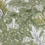 Close-up of the Snakeshead Floral polyester cushion in Sunflower/Stone, showing the mirrored botanical print in green, gold and cream on a stone fabric ground.
