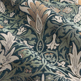 Close-up of Snakeshead Jacquard Chenille pencil pleat curtain fabric in Indigo/Leaf, showing folded chenille with flame-like flowers and scrolling foliage in green and indigo tones.