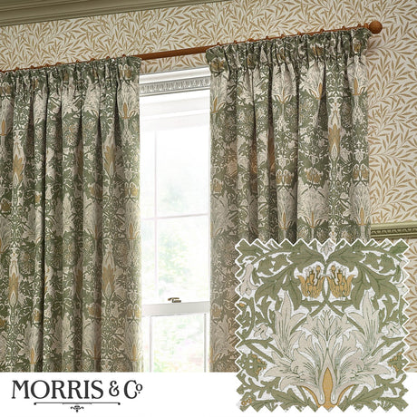 Snakeshead Chenille Pencil Pleat Curtains in Sunflower/Stone, shown hung on a wooden pole in a living room, featuring a green and gold jacquard foliage pattern with pleated heading.