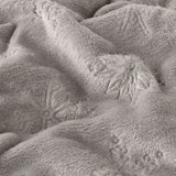 Close-up of the Snowflakes Plain Faux Fur Throw in grey, showing soft fleece pile with an embossed snowflake pattern raised against the folded fabric surface.