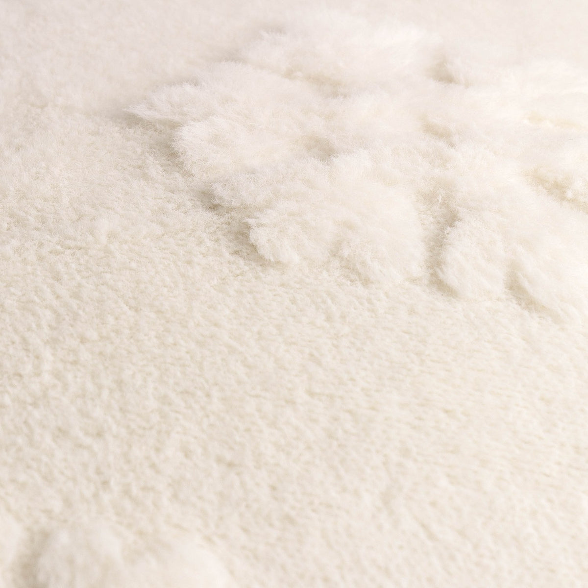 Close-up of the Snowflakes Faux Fur Polyester Velvet Throw in snow white, showing a raised snowflake motif standing proud of the dense, long-piled surface.