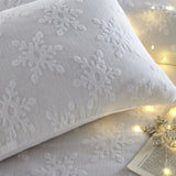 Close-up of the Snowflake Cotton Abstract Duvet Cover Set in white, showing tufted snowflake texture on a pillow, styled with fairy lights on the bed.