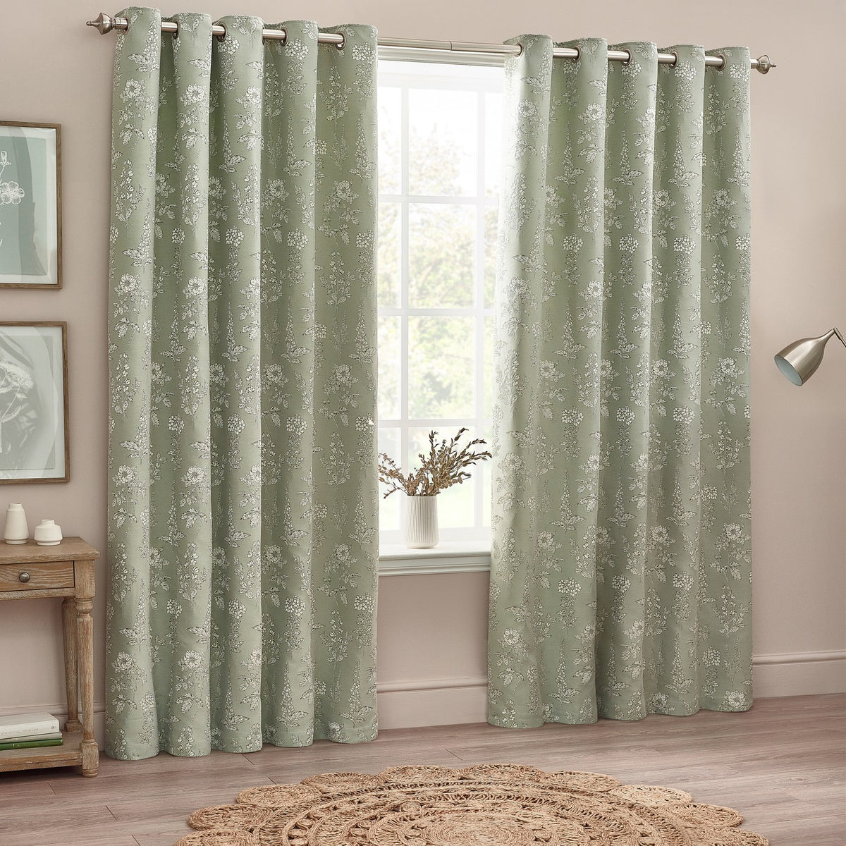 Sophia Jacquard Embroidered Eyelet Curtains in sage green with floral pattern and eyelet header, shown framing a window in a bedroom setting.