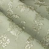 Close-up of Sophia Jacquard Embroidered Eyelet Curtains in sage green, showing woven botanical pattern of foxgloves, roses and leaves on folded polyester fabric.
