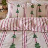 Spruce Stripes Cotton Reversible Duvet Cover Set in Oat on a bed, showing brushed cotton fabric with green Christmas trees between pink and green vertical stripes, with matching pillowcases.