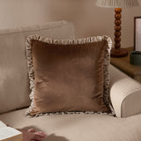 Solene Ruffle Velvet Linen Cushion in truffle brown with striped ruffle trim, matt velvet face, shown on a beige sofa beside a lamp table.