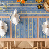 Sea Shells Printed Polyester Table Runner in blue with yellow stripes, scallop shell and floral motifs, styled on a dining table with matching placemats and napkins.