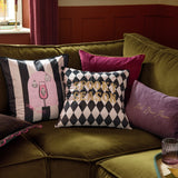 Spooky Spritz striped velvet cushion in pink and mono, with ghost cocktail glass design, styled on an olive green sofa alongside patterned scatter cushions.