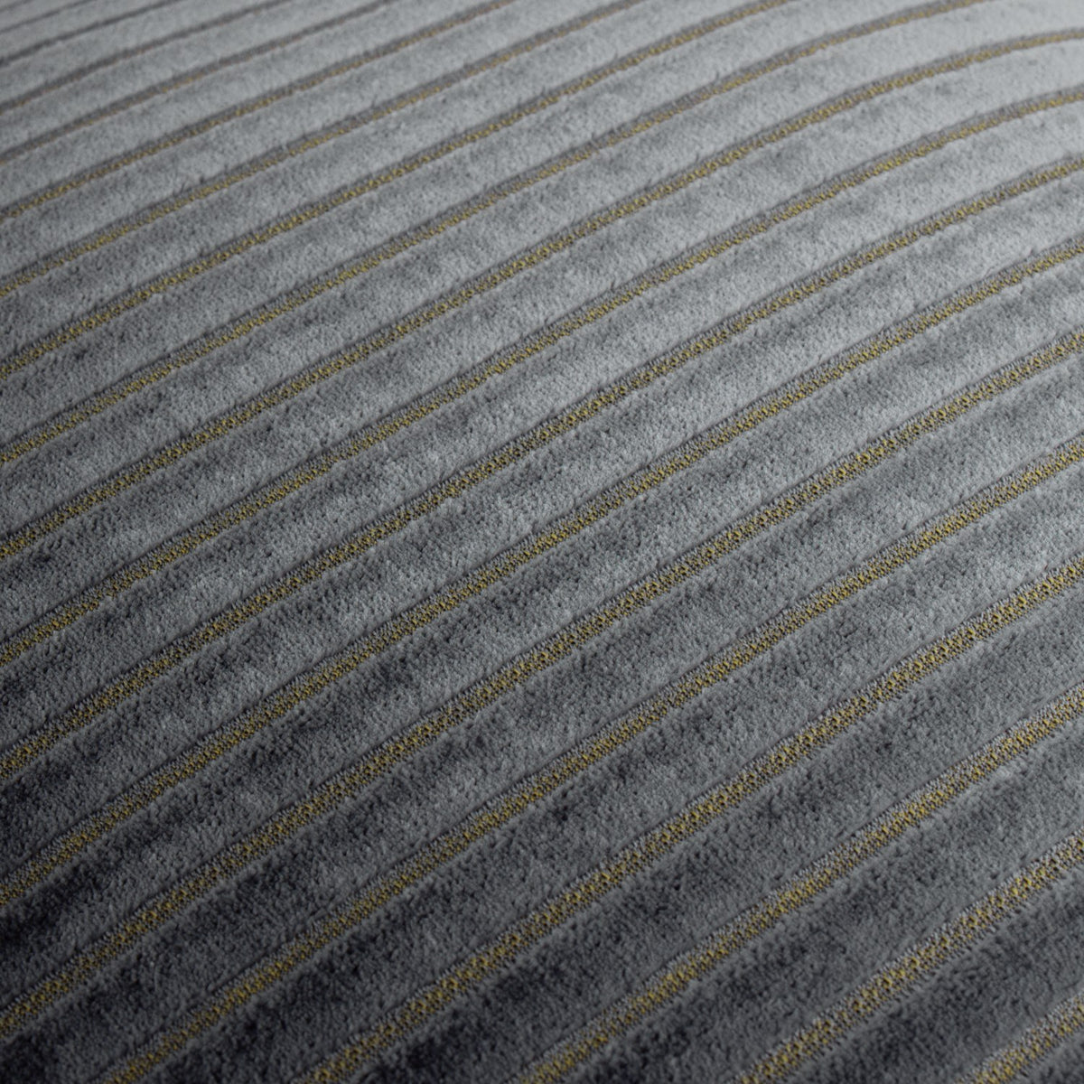 Close-up of the Savoy Stripe cushion in charcoal grey polyester velvet, showing cut-pile diagonal stripes with fine gold metallic threads running through the flatter channels.