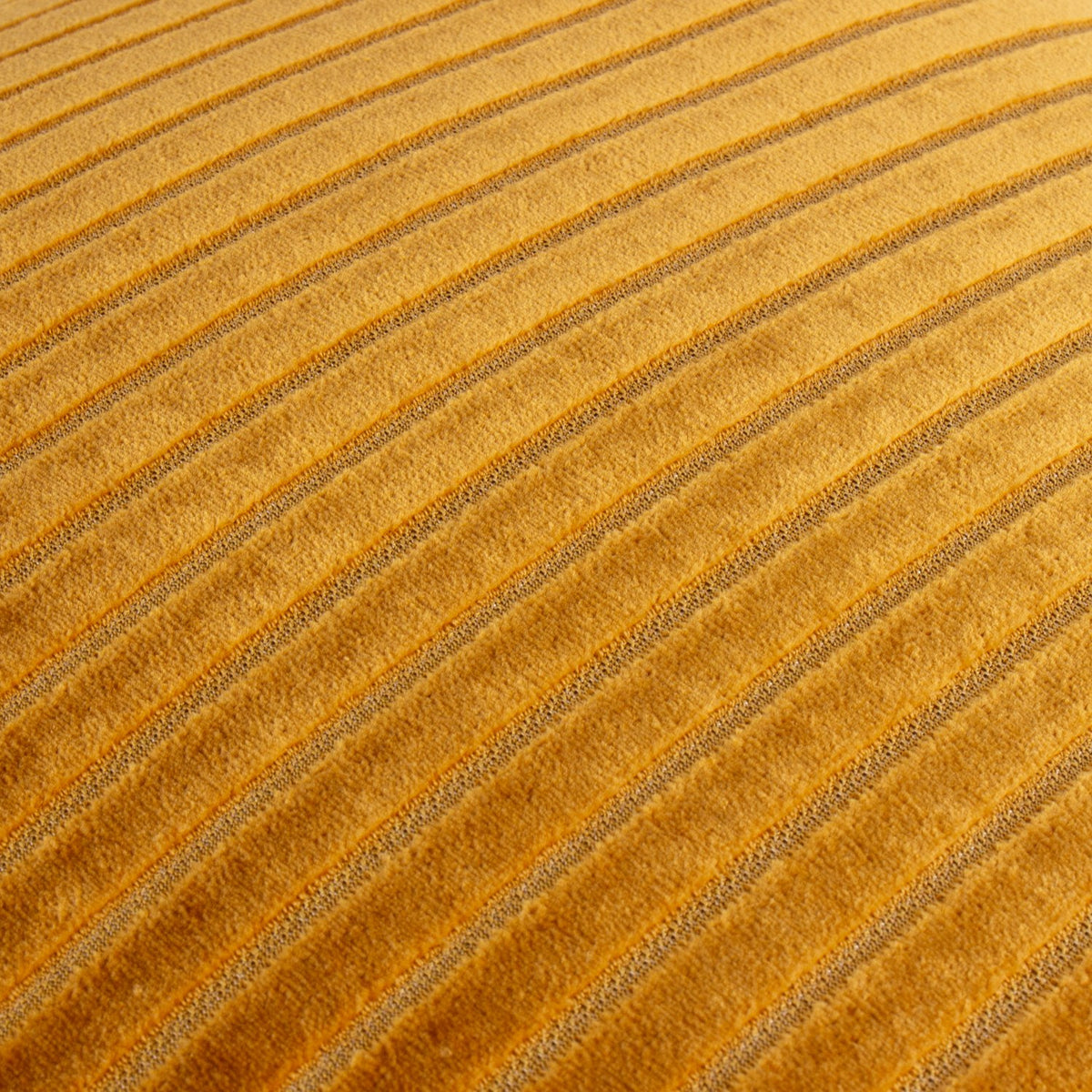 Close-up of the Savoy Stripe cushion in gold polyester velvet, showing raised cut-velvet ribs with recessed channels catching the light diagonally.
