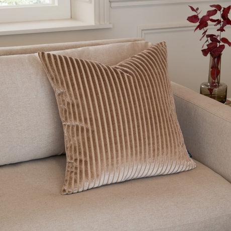 Savoy Stripe Polyester Velvet Cushion in mink, a square cushion with cut-pile stripe texture, shown propped on a beige sofa in a living room setting.