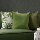 Stitch Plain Velvet Cushion in grass green with pale contrast blanket-stitch edging, shown on a green sofa beside patterned and textured cushions.