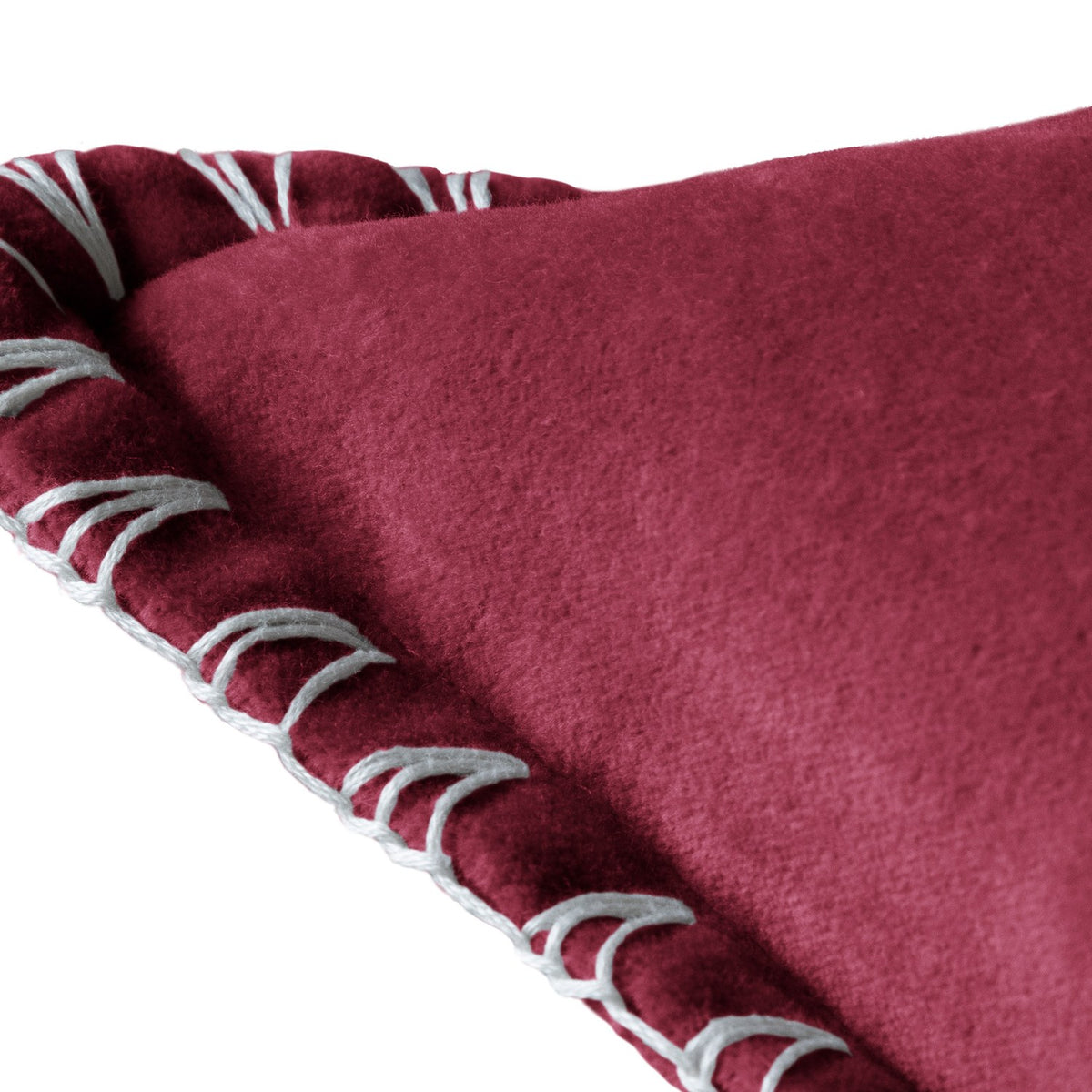 Close-up of the Stitch Plain Velvet Cushion in pomegranate red velvet, showing the smooth fabric texture and hand-worked blanket stitch edge in pale grey thread against a white background.