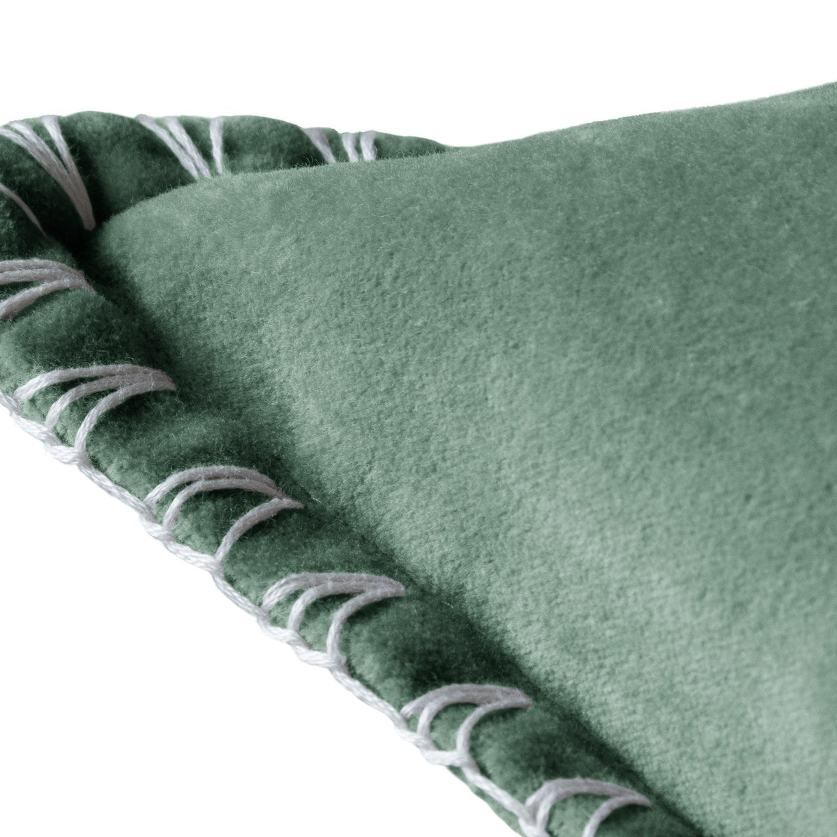 Close-up of the Stitch Plain Velvet Cushion in seafoam green velvet, showing the folded corner edge with hand-worked ivory blanket stitch trim on a white background.
