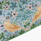 Strawberry Thief cushion corner, mineral-blue polyester fabric with golden thrushes, floral blossoms and green scrollwork, edged in a solid green border.