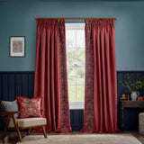 Berry red velvet pencil pleat curtains with pencil pleat heading and an embroidered Strawberry Thief leading edge, styled in a living room beside a window.