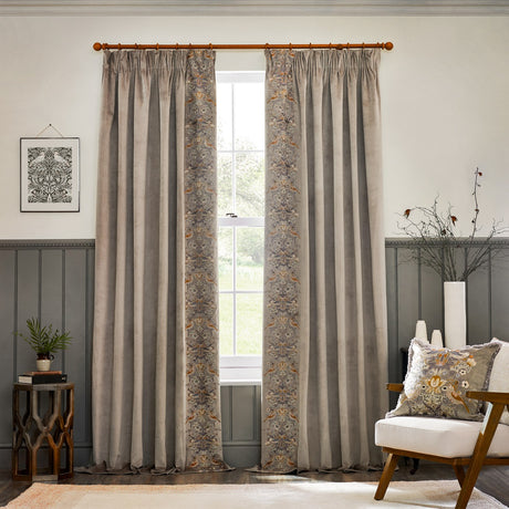 Biscuit velvet pencil pleat curtains with embroidered Strawberry Thief leading edge, hung on a wooden pole in a living room with panelled walls.