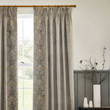 Strawberry Thief Velvet Pencil Pleat Curtains in biscuit, hung at a window with pencil pleat heading and an embroidered leading edge featuring birds and floral motifs.