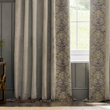 Strawberry Thief pencil pleat curtains in biscuit velvet with embroidered bird and floral leading edge, shown pleated beside a window overlooking greenery.