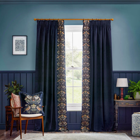 Indigo velvet pencil pleat curtains with Strawberry Thief bird and floral embroidery along the leading edge, styled either side of a window in a blue-toned living room.