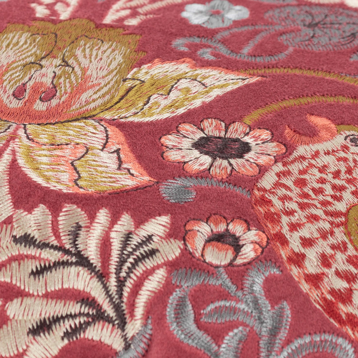 Close-up of the Strawberry Thief Jacquard Velvet Cushion in Berry, showing birds, strawberries and florals embroidered in gold, coral, grey and cream on a deep red velvet ground.