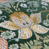 Close-up of the Strawberry Thief jacquard velvet cushion in forest green, showing dense embroidered floral and leaf detail in cream, gold and rust tones.