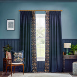 Strawberry Thief Jacquard Velvet Cushion in indigo on a wooden armchair, showing mirrored bird and floral embroidery in cream, gold and rust on a deep blue velvet ground.