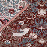 Strawberry Thief Jacquard Cotton Throw in Berry, folded corner showing bird, strawberry and floral motifs on deep berry-red ground with cream reverse in soft blue and green.