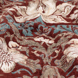 Close-up of the Strawberry Thief Jacquard Cotton Throw in Berry, showing woven birds and florals in cream, blue and brown on a deep red ground.