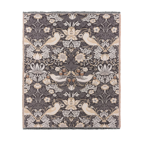 Strawberry Thief Jacquard Cotton Throw in Biscuit, showing birds, flowers and strawberries woven in cream and beige on a charcoal ground with fringed edges, on a plain white background.
