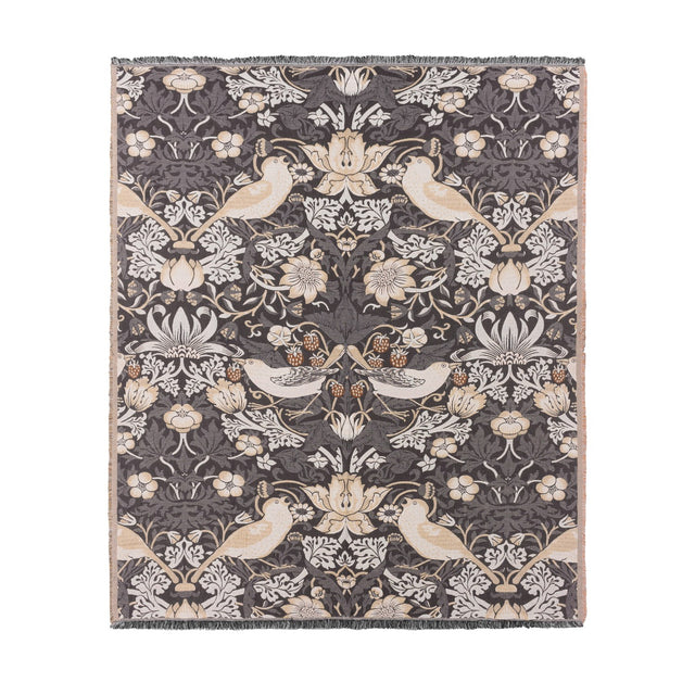 Strawberry Thief Jacquard Cotton Throw in Biscuit, showing birds, flowers and strawberries woven in cream and beige on a charcoal ground with fringed edges, on a plain white background.