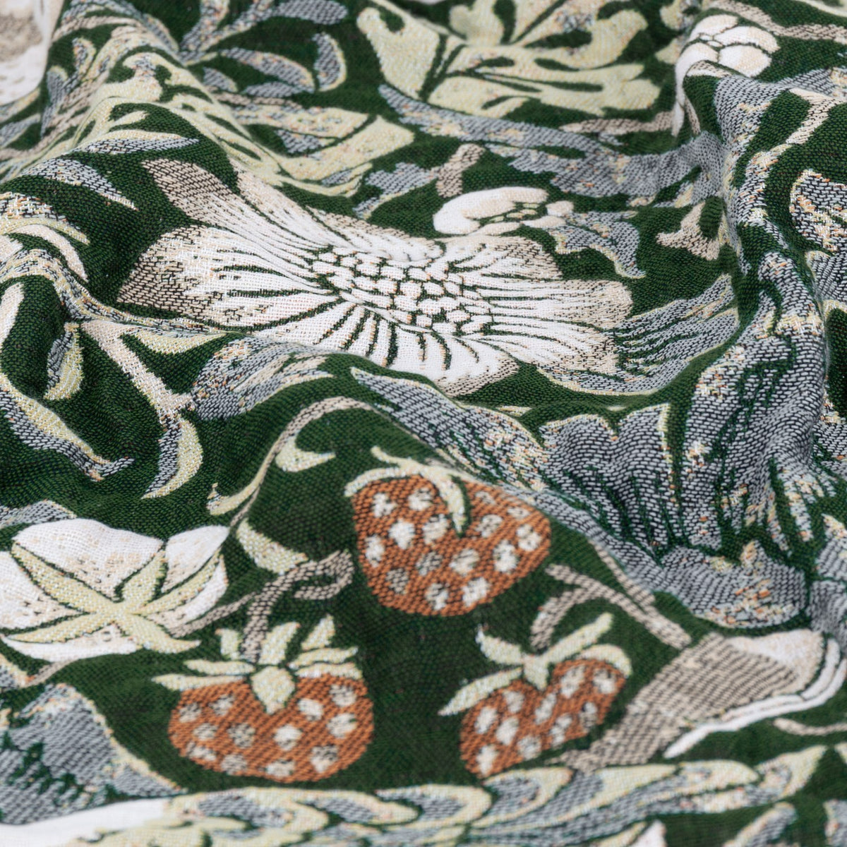 Strawberry Thief Jacquard Cotton Throw in Forest Green, close-up of woven fabric showing birds, strawberries and foliage in cream, grey and rust tones.