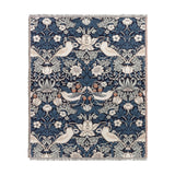 Strawberry Thief Jacquard Cotton Throw in indigo, woven with birds, strawberries and trailing floral motifs in cream, rust and blue tones, with fringed edges on a white background.
