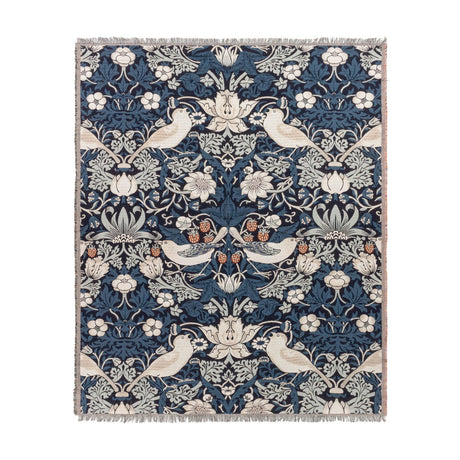 Strawberry Thief Jacquard Cotton Throw in indigo, woven with birds, strawberries and trailing floral motifs in cream, rust and blue tones, with fringed edges on a white background.