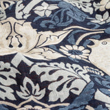Close-up of the Strawberry Thief Jacquard Cotton Throw in indigo, showing woven bird, floral and berry motifs in cream and blue tones on a dark ground.