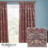 Strawberry Thief pencil pleat curtains in berry red jacquard fabric with bird and floral pattern, shown hanging from a wooden pole beside a window in a blue-walled room, with fabric swatch inset.