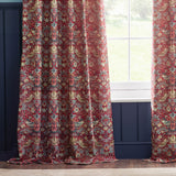 Strawberry Thief pencil pleat curtains in berry red jacquard fabric with bird and floral pattern, hung pleated at a window beside navy panelled walls.