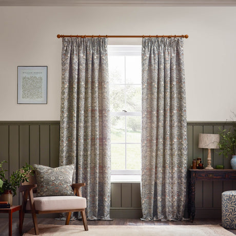 Strawberry Thief pencil pleat curtains in biscuit, jacquard-woven bird and foliage pattern in grey and brown, shown pole-hung either side of a window in a living room.