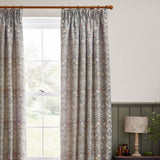 Strawberry Thief pencil pleat curtains in biscuit, jacquard-woven bird and foliage pattern in grey, cream and brown, shown pleated on a wooden pole beside a window.