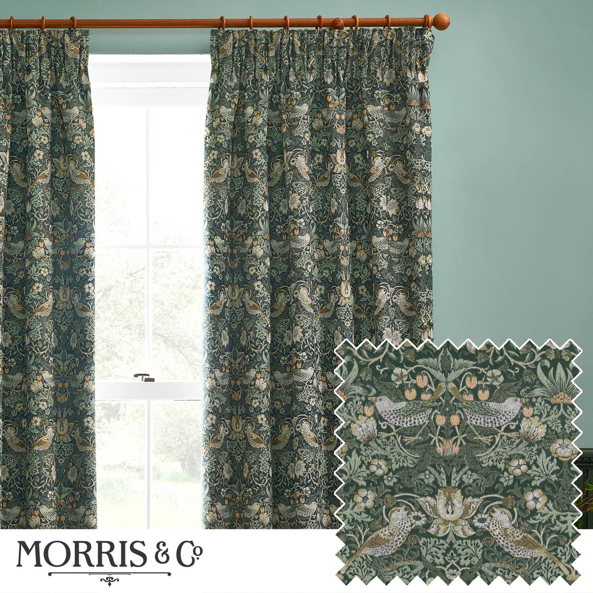 Pencil pleat curtains in Strawberry Thief forest green fabric with bird and floral pattern, shown hanging on a wooden pole beside a window.