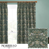 Pencil pleat curtains in Strawberry Thief forest green fabric with bird and floral pattern, shown hanging on a wooden pole beside a window.