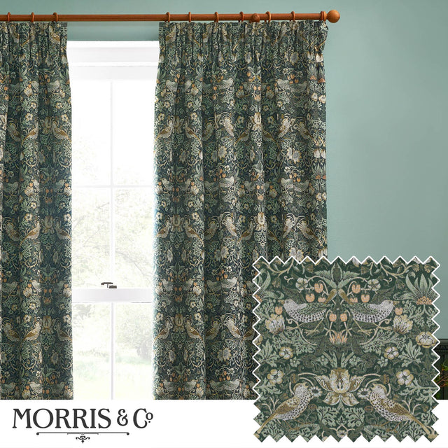Pencil pleat curtains in Strawberry Thief forest green fabric with bird and floral pattern, shown hanging on a wooden pole beside a window.